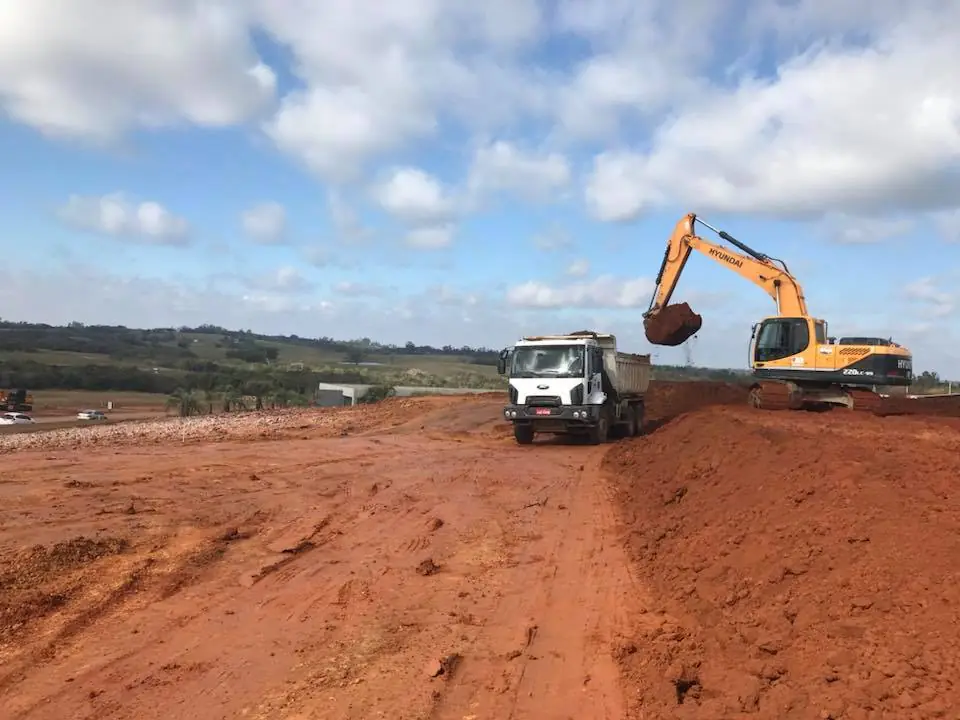 Escavadeira carregando caminhão em obra de terraplenagem
